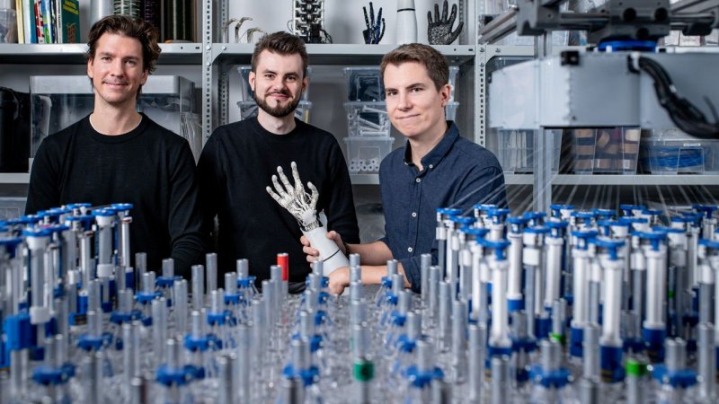 Members of the Allonic team with robotic-hand technology